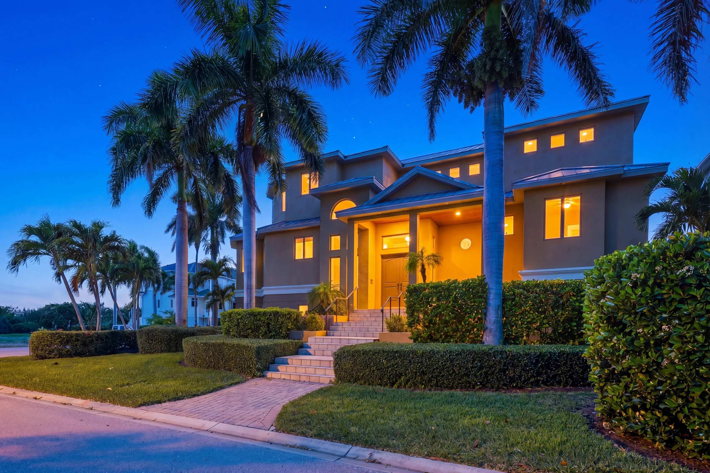 Palm-lined home illuminated at dusk photographed by Vuzario
